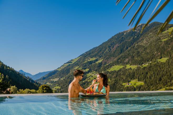 Mann füttert Frau mit Obst im Pool