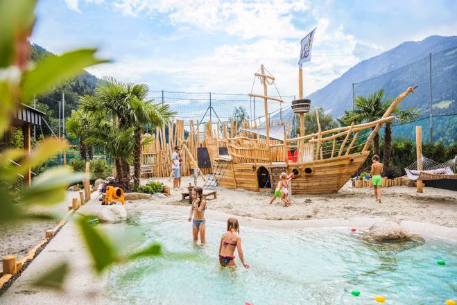 Kinder spielen am Holzschiff im Wasser