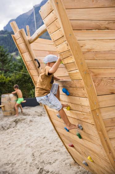 Junge klettert in Holzschiff auf einem Spielplatz