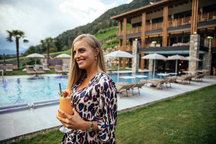 Frau am Pool hält einen Cocktail in der Hand