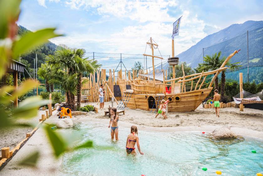 Kinder spielen am Holzschiff im Wasser