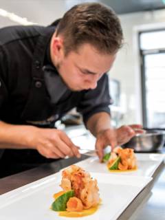 Koch drapiert Fisch auf einen Teller