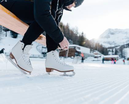Frau zieht Schlittschuhe im Schnee an