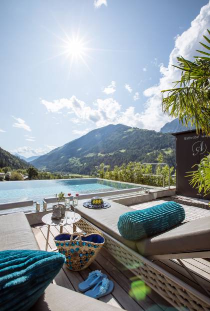 Sonnenliegen am Infinitypool mit Blick auf die Alpen