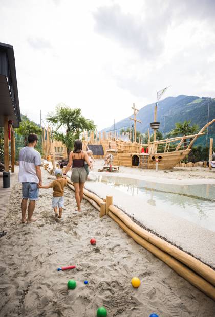 Familie läuft zum Holzschiff und Spielplatz für Kinder