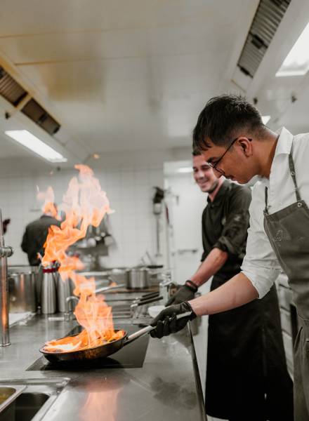 Koch flambiert in einer Pfanne