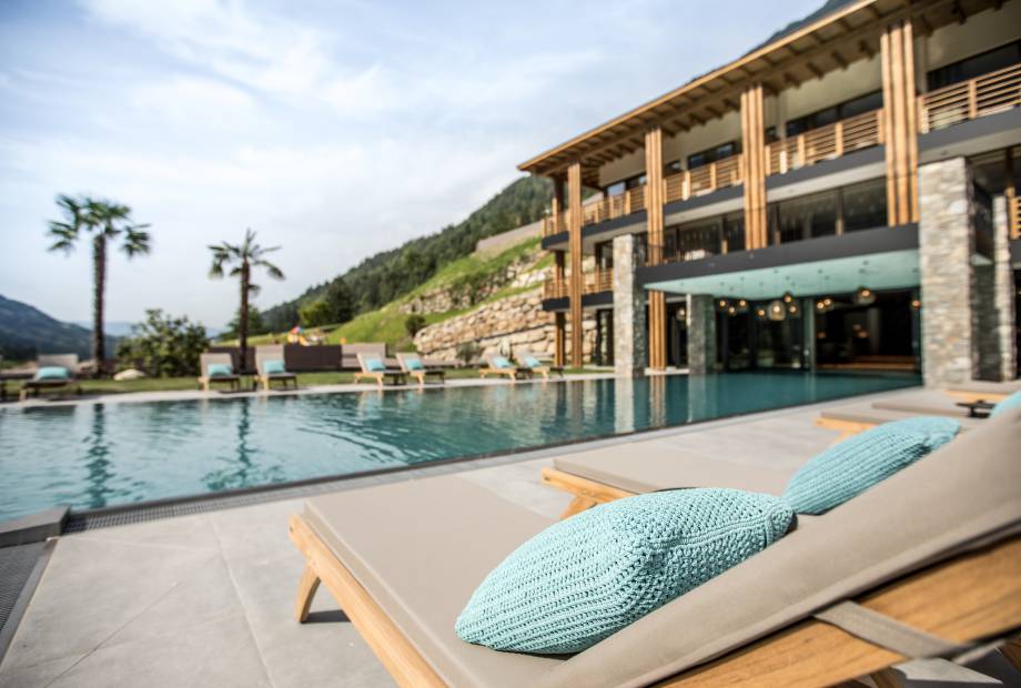 Sonnenliege am Pool mit Blick auf das Hotel Sonnenalm