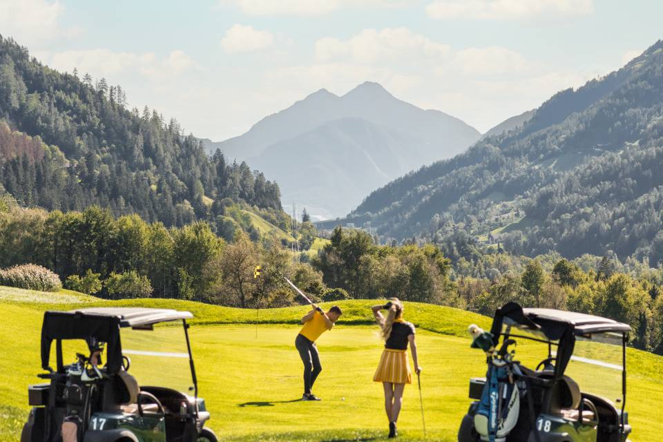 Paar beim Golfen mit Blick auf die Alpen