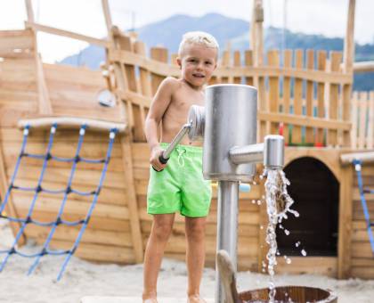 Junge pumpt Wasser aus Brunnen