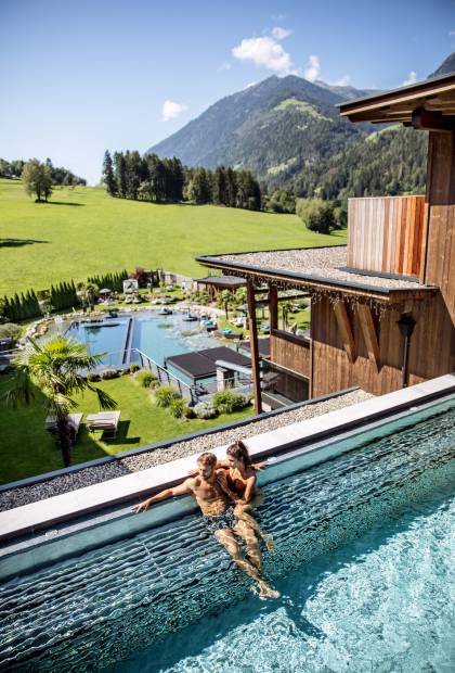 Paar entspannt im Outdoor Pool mit Blick auf die Sürdtiroler Alpen