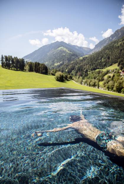 Mann taucht im Pool mit Blick auf die Südtiroler Alpen